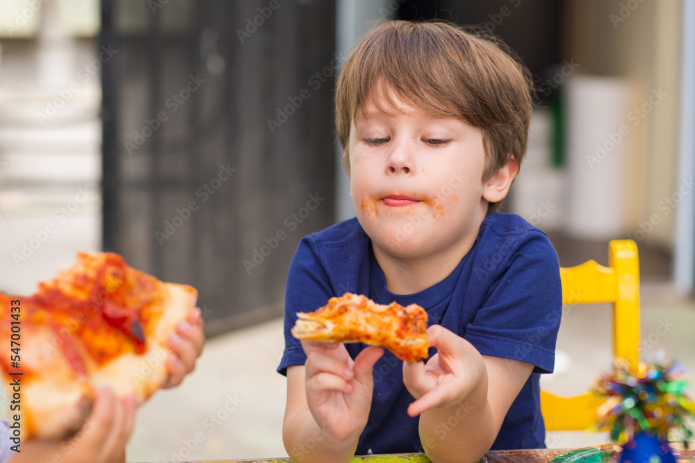 A kid eats a pizza. Handsome boy has a Happy Birthday party. Portrait of a Preschool smiling Boy. A kid eats a pizza. Handsome boy has a Happy Birthday party. Portrait of a Preschool smiling Boy.
