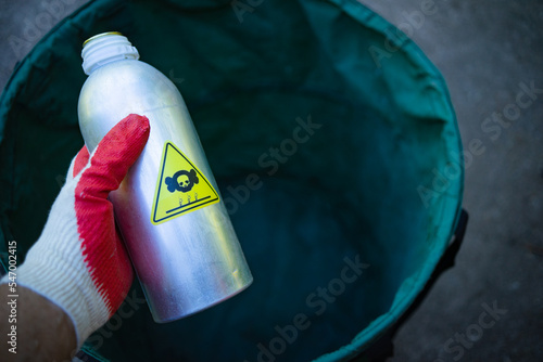 Disposal of toxic contaminated waste. A gloved hand throws out a metal bottle with an infected substance.