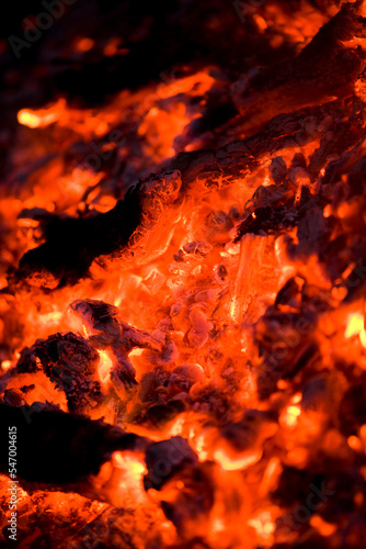 Burning hot coals and ash radiating heat with a narrow focus depth of field.