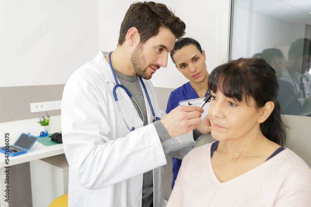 doctor holding otoscope and examining ear of senior woman doctor holding otoscope and examining ear of senior woman