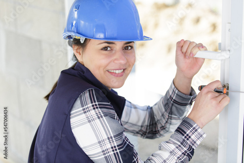 Fotografía portrait of young woman fixing door with screwdriver