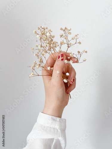Pomalowane paznokcie w kwiatki czerwone na beżowym tle, maki, gipsówka, romantyczny manicure, lakier do paznokci, wiosna, dłoń trzymająca kwiat