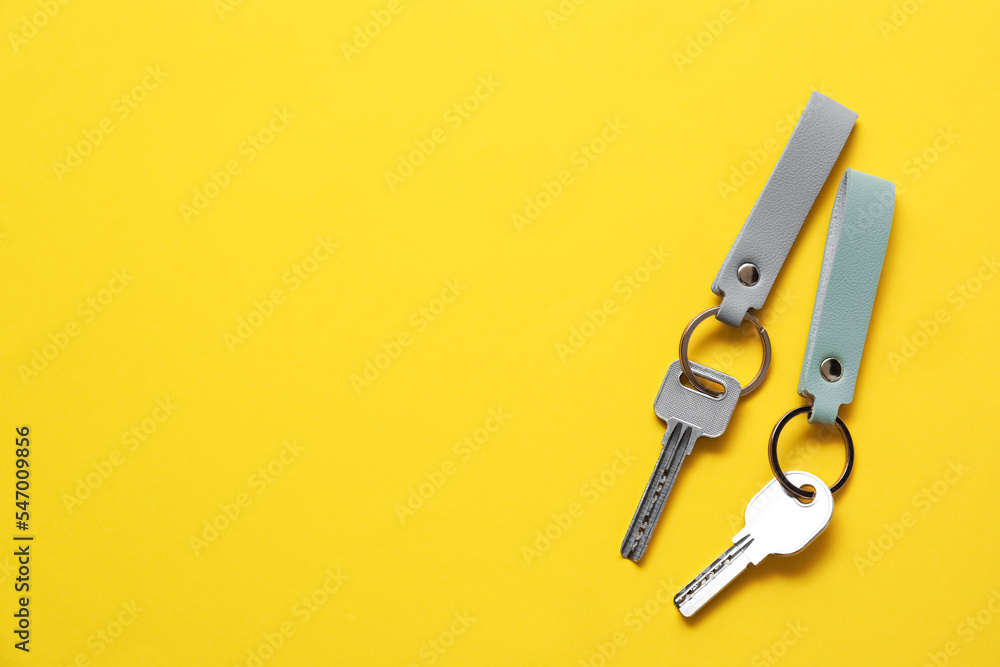 Keys with leather keychains on yellow background Keys with leather keychains on yellow background