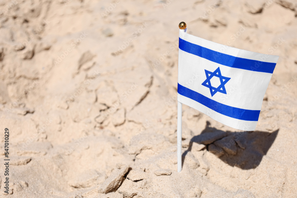 Naklejka premium Flag of Israel on sand, closeup