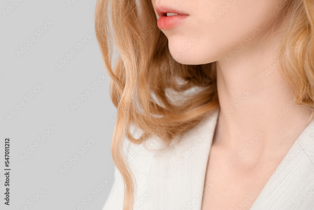 Young blonde woman with curly hair in stylish jacket on light background, closeup Young blonde woman with curly hair in stylish jacket on light background, closeup