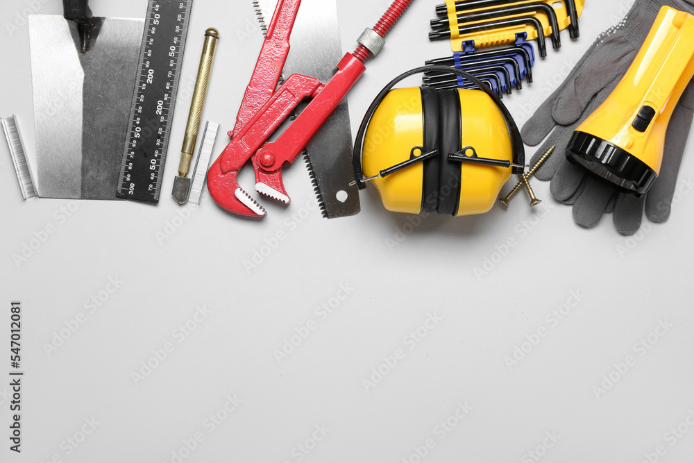 Hearing protectors with builder's tools on grey background