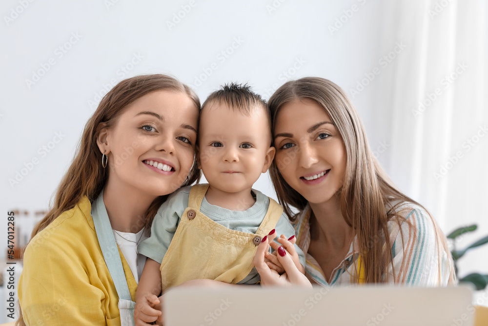 Happy lesbian couple with their little baby in kitchen Happy lesbian couple with their little baby in kitchen