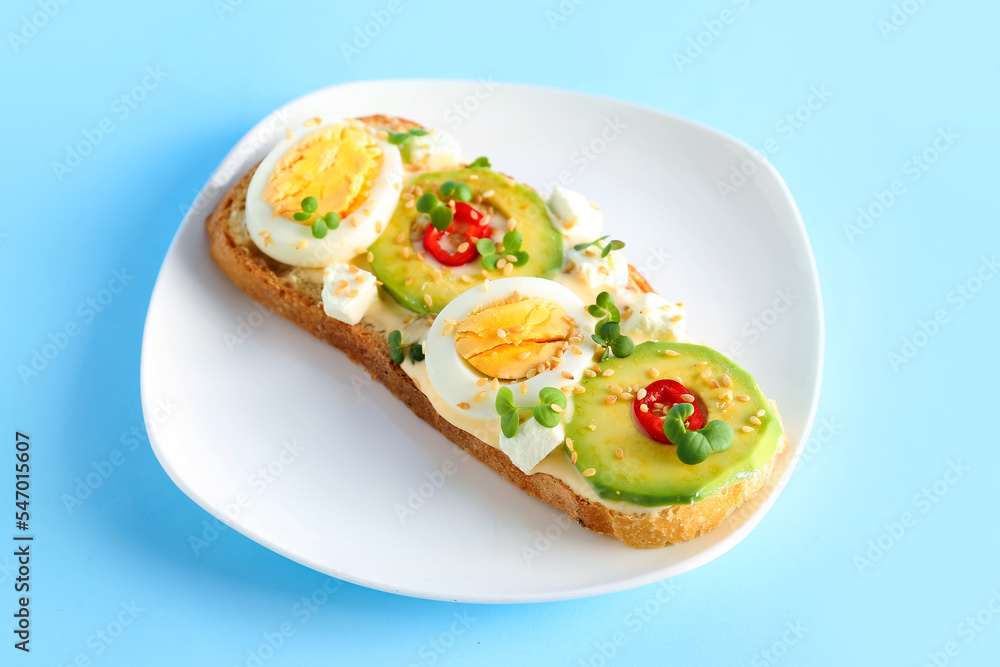 Plate of tasty toast with boiled egg and avocado on color background