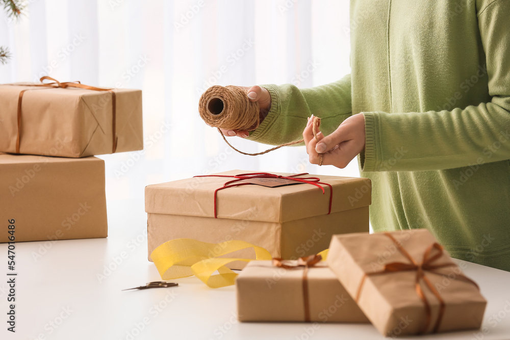 Fototapeta premium Woman with rope and Christmas gift box at table, closeup