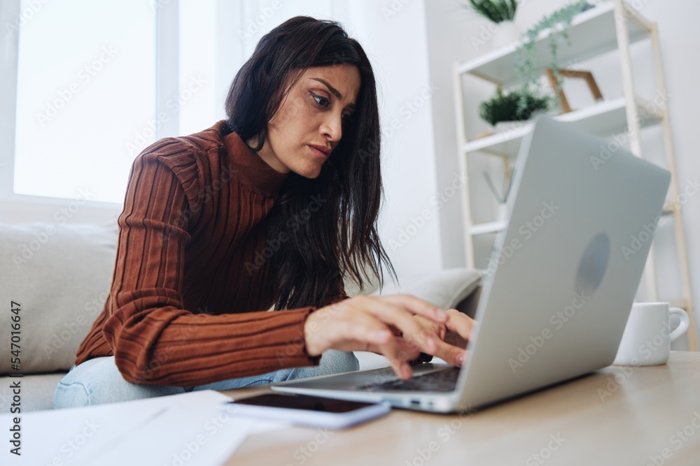 A woman does financial calculations and document analysis at home with a laptop, a freelancer works over the Internet in a home office A woman does financial calculations and document analysis at home with a laptop, a freelancer works over the Internet in a home office
