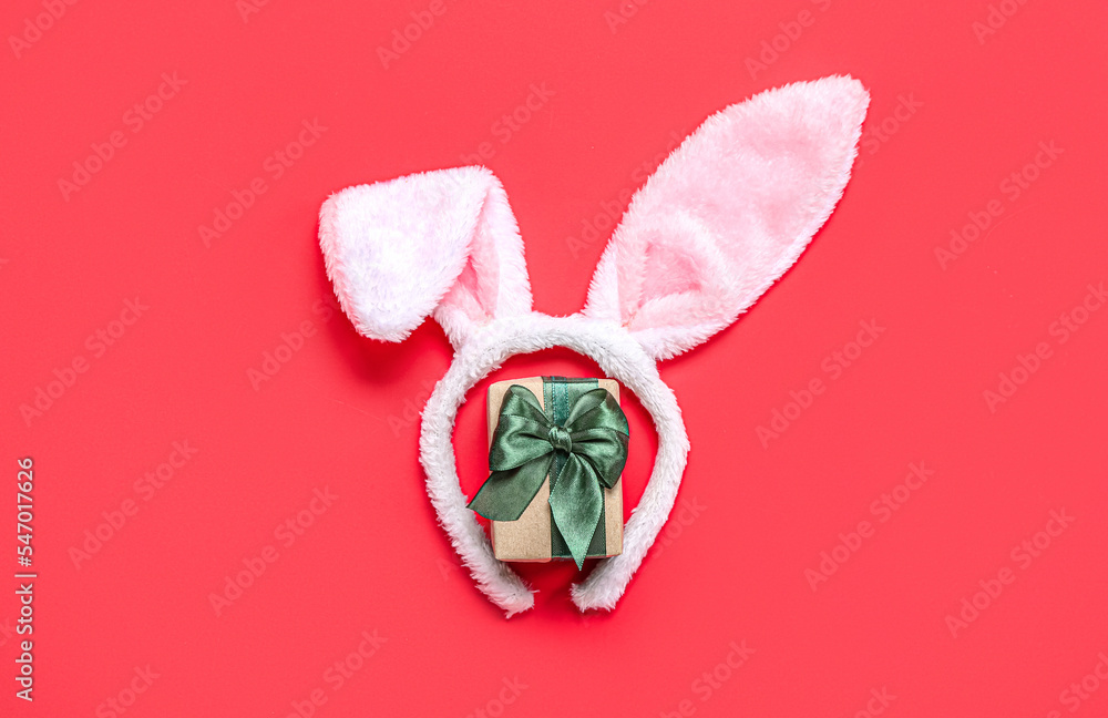 Bunny ears with Christmas gift on red background
