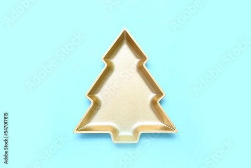 Beautiful plate in shape of Christmas tree on blue background