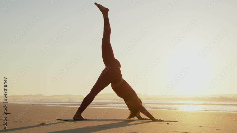 Caucasian woman stretching and practicing yoga asana while exercising at the beach