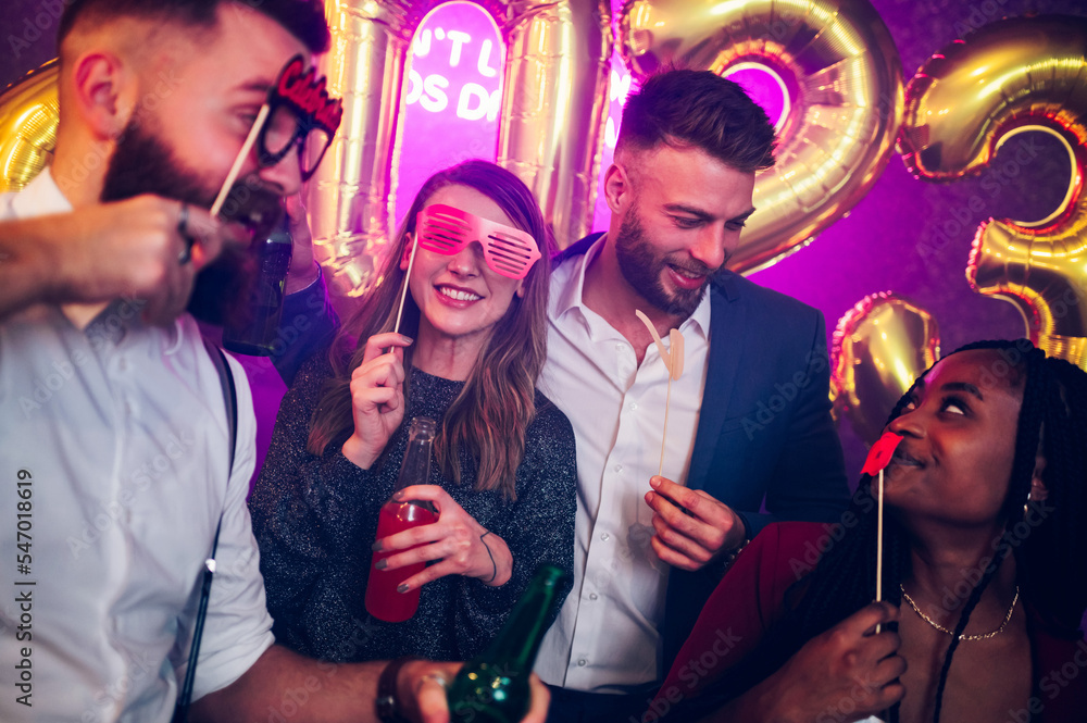 Multiracial friends celebrating new years eve with party props and drinks in the club Multiracial friends celebrating new years eve with party props and drinks in the club