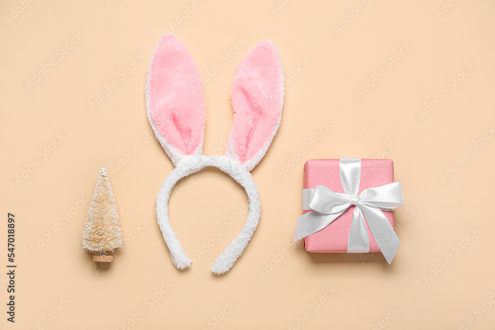 Bunny ears with Christmas tree and gift on beige background