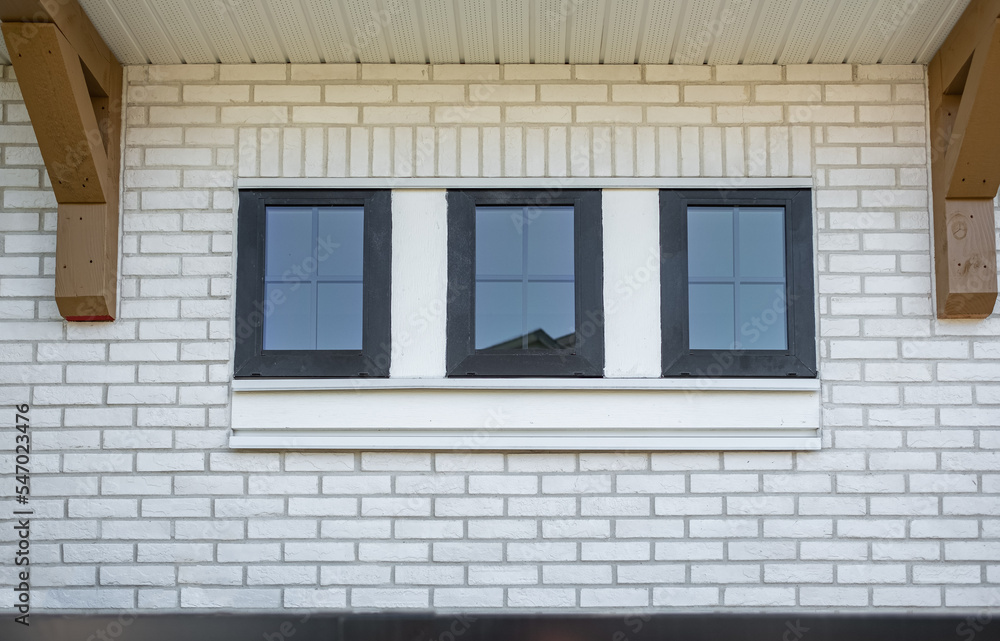 Small windows on white wall, minimalistic with copy space. Small white wooden three window frame on a white brick wall