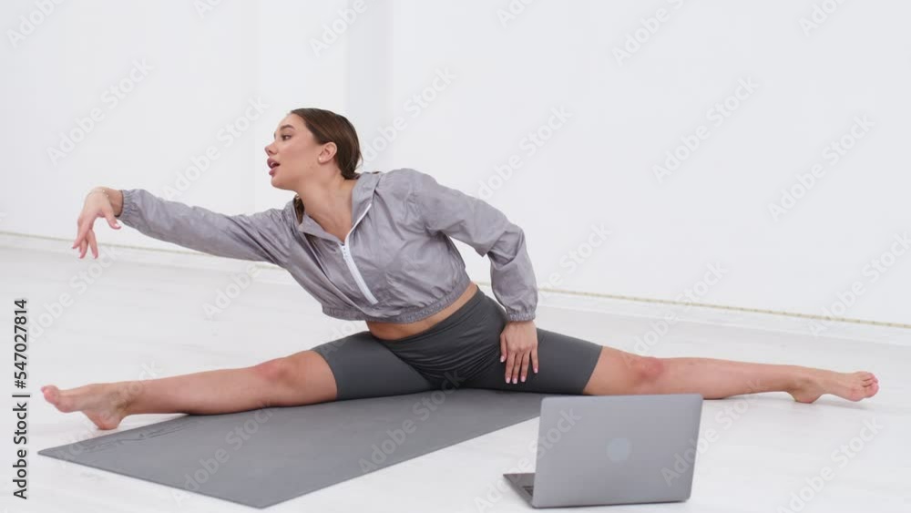 A young beautiful female trainer, stretches and practices stretching and yoga with a student through a video call in a bright sunny gym. The concept of a healthy lifestyle, fitness, well-being A young beautiful female trainer, stretches and practices stretching and yoga with a student through a video call in a bright sunny gym. The concept of a healthy lifestyle, fitness, well-being