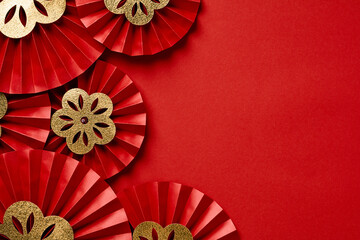 Chinese New Year festive paper fans with gold flowers on red background.