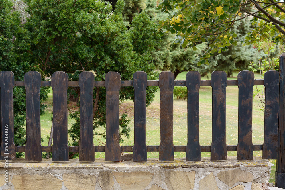 Low wooden shabby fence near trees outdoors Low wooden shabby fence near trees outdoors