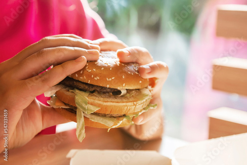 WARSAW, POLAND - SEPTEMBER 16, 2022: Woman with McDonald's burger at table in cafe, closeup photo