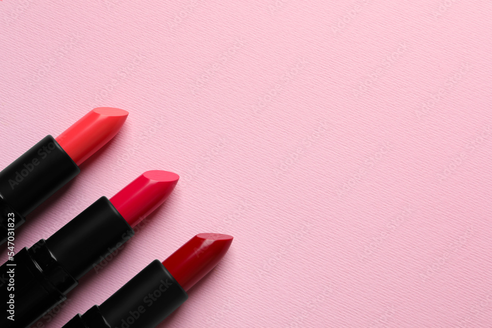 Many bright lipsticks on pink background, flat lay. Space for text Many bright lipsticks on pink background, flat lay. Space for text