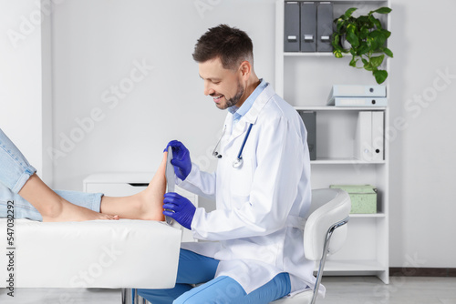 Male orthopedist fitting insole to patient's foot in hospital