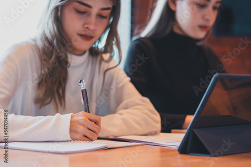 Photography Teenage Asian girl student studying online write on a notebook with a laptop on