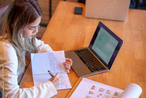 Canvas Print Teenage Asian girl student studying online write on a notebook with a laptop on