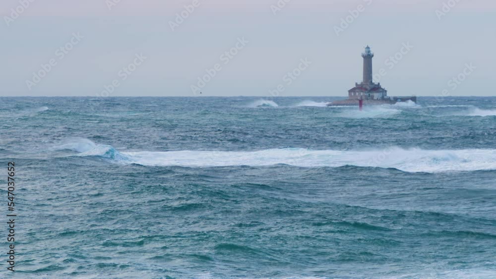 Lighthouse Porer on stormy weather, big waves making crests, grebes flying through restless sea Lighthouse Porer on stormy weather, big waves making crests, grebes flying through restless sea