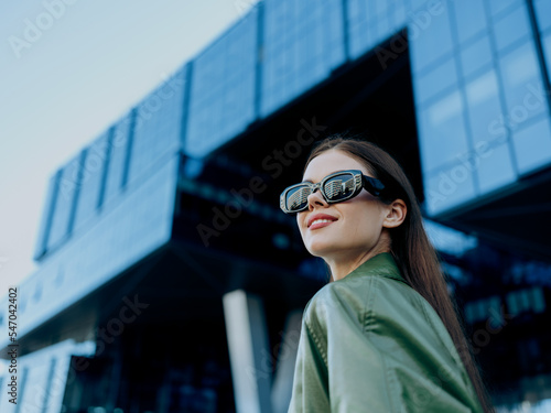 Portrait of a woman against the glass business buildings in the city wearing black fashion sunglasses