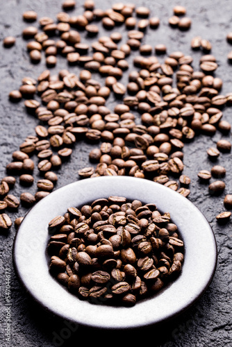 Roasted coffee beans on a plate, on a dark background, close-up image, space for text