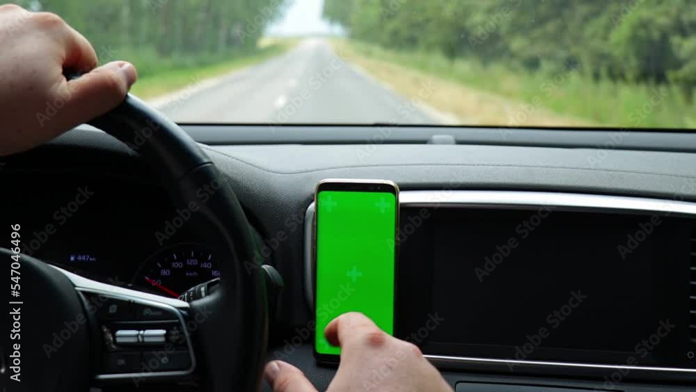 Man driving car and using smartphone with empty green screen. Searching location via gps navigator application. Concept for communication technology. Man driving car and using smartphone with empty green screen. Searching location via gps navigator application. Concept for communication technology.