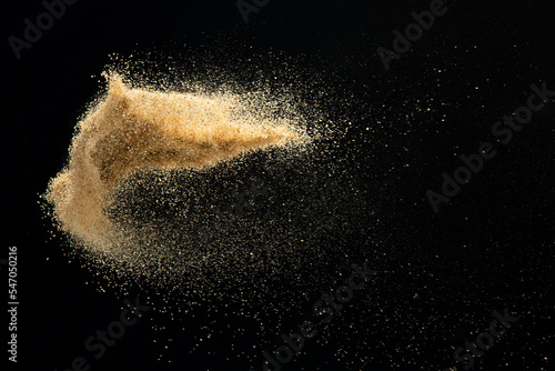 Sand flying explosion, Golden sand wave explode. Abstract sands cloud fly. Yellow colored sand splash throwing in Air. Black background Isolated high speed shutter, throwing freeze stop motion