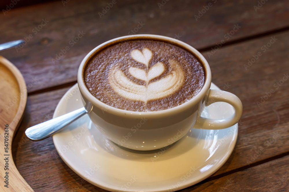 Hot coffee latte with latte art milk foam in cup mug on wood desk on top view. As breakfast In a coffee shop at the cafe,during business work concept Hot coffee latte with latte art milk foam in cup mug on wood desk on top view. As breakfast In a coffee shop at the cafe,during business work concept