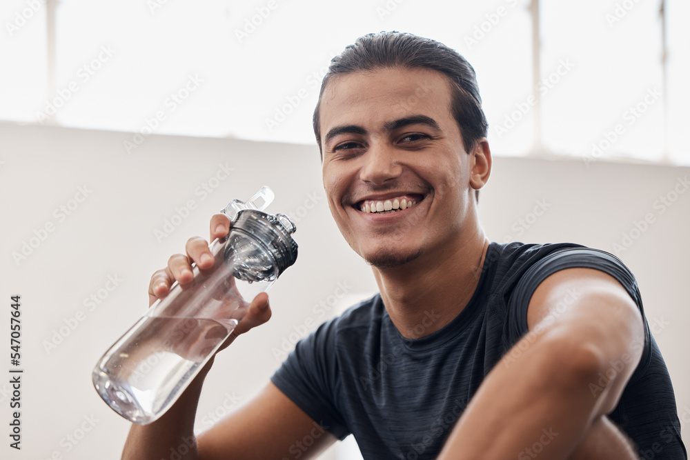 Muscular man holding his water bottle and resting from workout