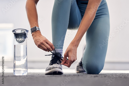Fototapeta Naklejka Na Ścianę i Meble -  Fitness, woman and shoe for running preparation, workout or training exercise with water bottle in the outdoors. Female tying laces getting ready for sports exercising, run or healthy cardio outside