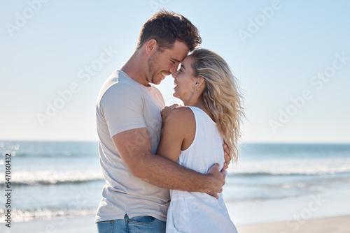 Couple, love and hug in relationship at the beach for summer vacation or romantic bonding in the outdoors. Happy man and woman hugging with smile together in loving embrace for romance by the ocean