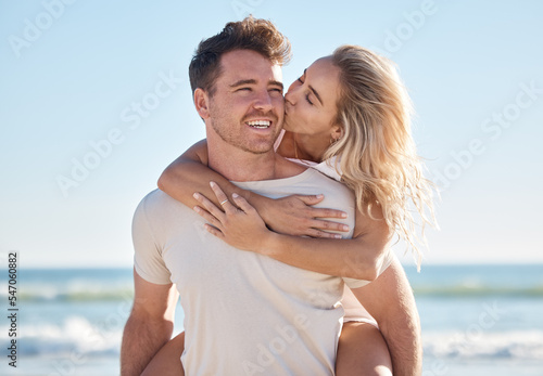 Beach love, hug and couple kiss on romantic date, bonding getaway or outdoor nature adventure for peace, freedom and fun. Ocean sea, blue sky and man and woman piggyback on Sydney Australia holiday