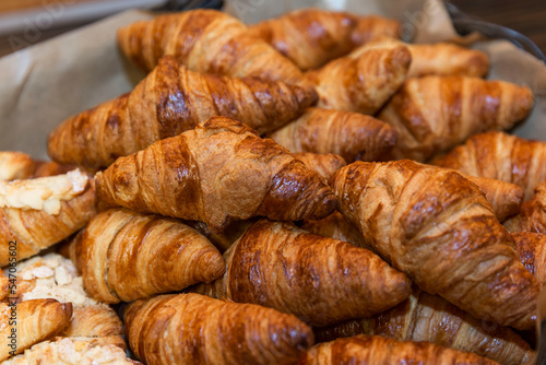 Many appetizing croissants in a basket on the buffet table. Close-up. Breakfasts and coffee breaks.