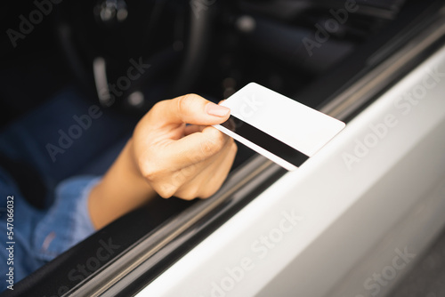 Close up of young woman holding credit card in car. She is paying with credit card.