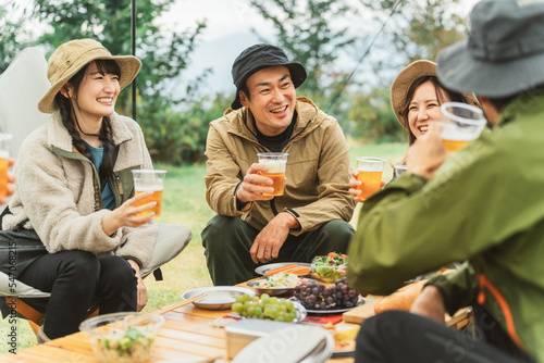 秋冬のキャンプ場で仲間と一緒にビールを飲んでパーティーするアジア人の男女 