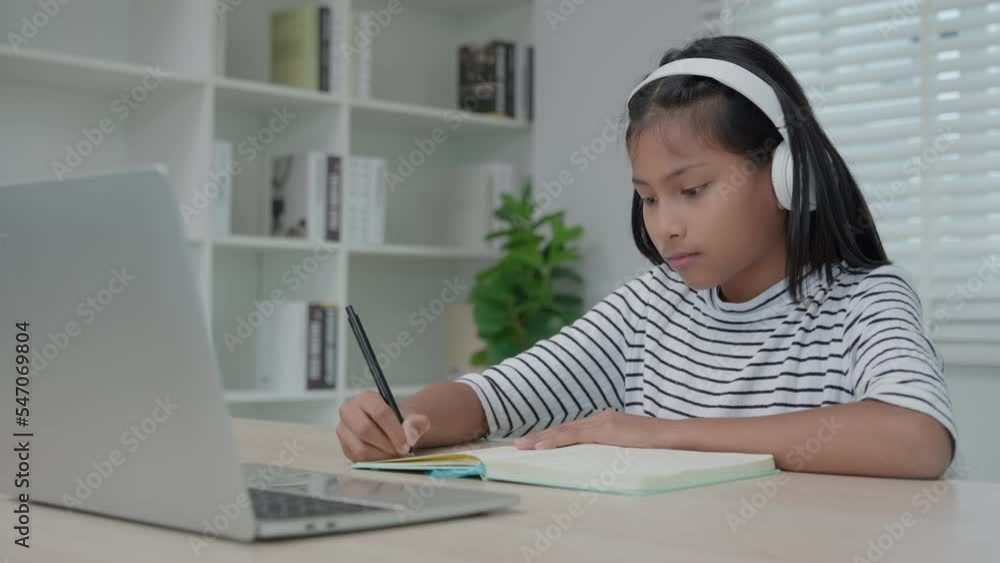 training and learing online course for Asian children. video conference on laptop at home. play back online course, girl student wear earphones to study, notes homework, video classes, new education. training and learing online course for Asian children. video conference on laptop at home. play back online course, girl student wear earphones to study, notes homework, video classes, new education.
