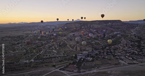 Göreme Turkey Aerial v44 flyover open fields overlooking at çavuşin village and mesa flat mountain at dawn with colorful hot air balloons flying high in the sky - Shot with Mavic 3 Cine - July 2022 photo