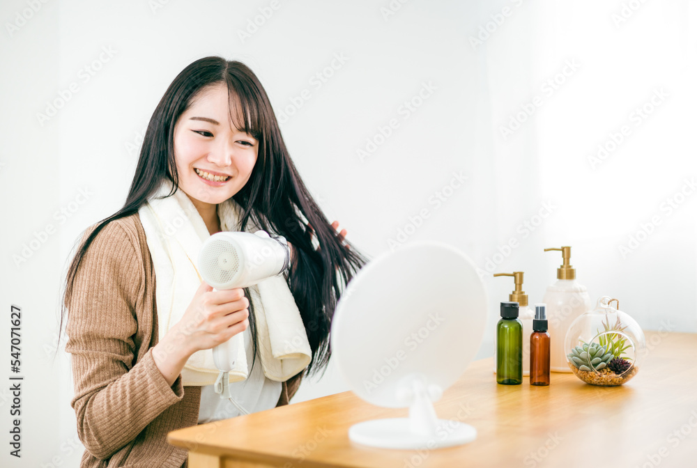 ドライヤーを使って髪を乾かす日本人女性
ドライヤーを使って髪を乾かす日本人女性