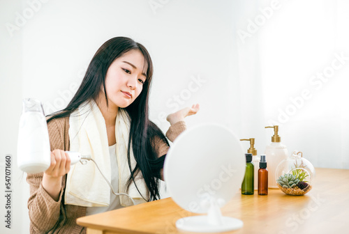 ドライヤーを使って髪を乾かす日本人女性（悩む） 