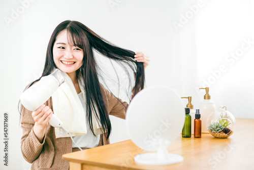ドライヤーを使って髪を乾かす日本人女性（笑顔） 
