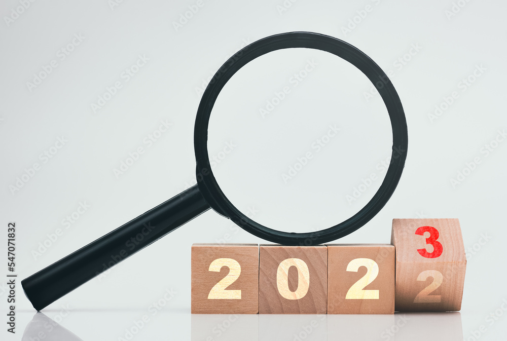 2023 wood block with magnifying glass on white background. 2023 wood block with magnifying glass on white background.