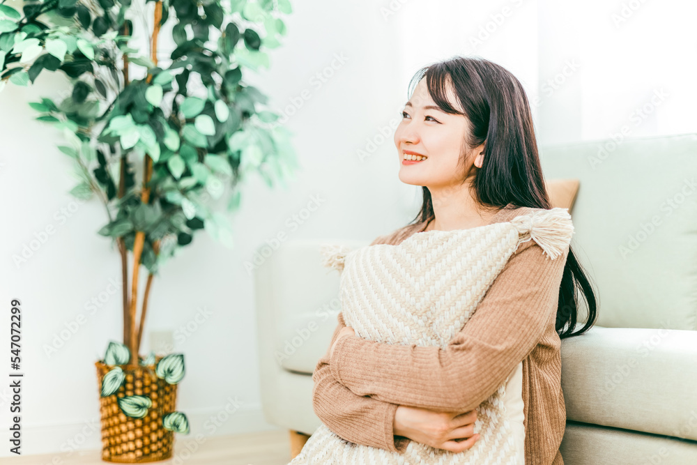 部屋のソファの下に座る笑顔の日本人女性
部屋のソファの下に座る笑顔の日本人女性