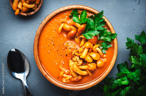 Spicy pumpkin carrot soup puree with mushrooms, pepper and parsley. Winter or autumn healthy vegan vegetarian food. Soup bowl on gray table background. Top view