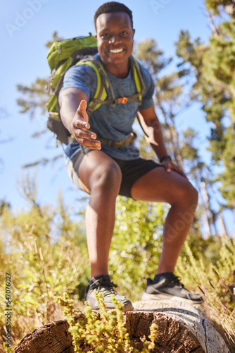 Black man, hiking and help hand, smile and happy outdoor in nature, forest or nature park in summer. Climbing up hill, trekking together in nature and healthy workout adventure, pov and fitness hiker photo